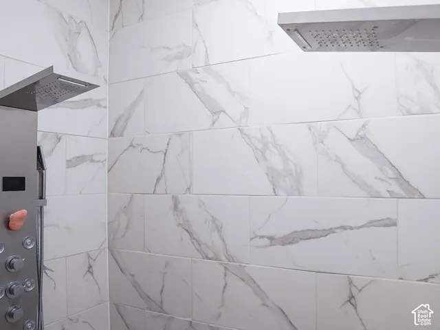 White marble-look wall tiling, dual rain shower heads, and an integrated shower panel