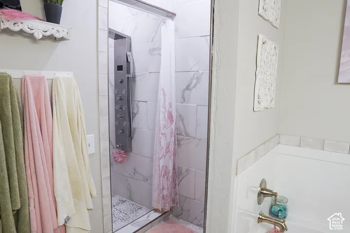 Shower with tiled surround, full-body shower panel, and glass enclosure