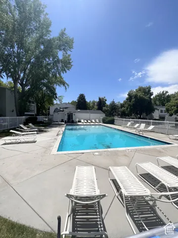 Rectangular swimming pool with a concrete surround and multiple lounge chairs
