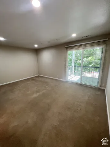 Recessed ceiling lighting illuminates a spacious room featuring wall-to-wall carpeting and neutral wall tones