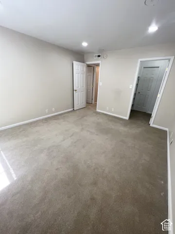 Carpeted room featuring neutral-toned walls, recessed lighting, and white paneled doors