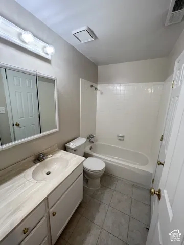 Bathroom featuring a vanity with a single sink, an integrated medicine cabinet, a full-size bathtub, and tile flooring