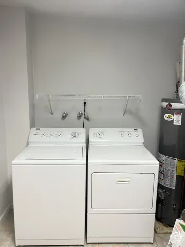 Laundry area featuring a top-load washing machine, front-load dryer, and wall-mounted wire shelving