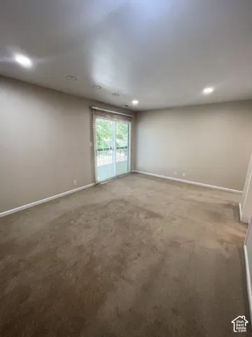 Recessed ceiling lighting, sliding glass door, white trim, and neutral wall paint