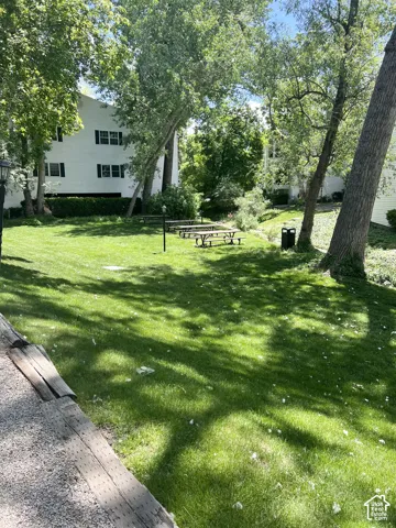 Expansive green space featuring multiple picnic tables and mature trees