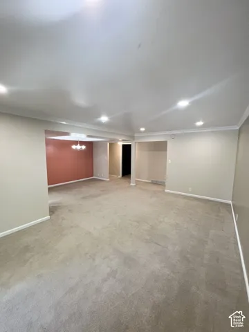 Recessed lighting, crown molding, neutral wall tones, and carpet flooring