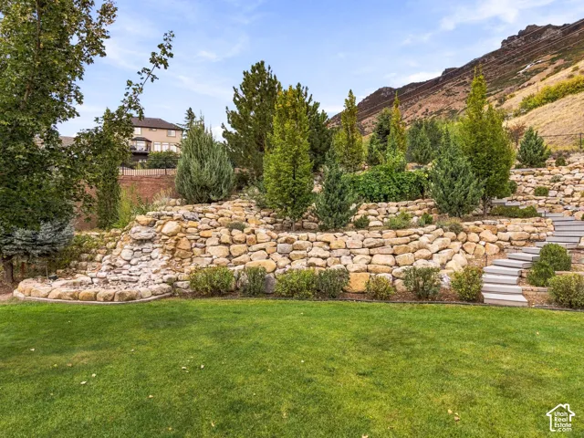 Tiered stone hardscaping with integrated plantings, a built-in water feature, and terraced steps