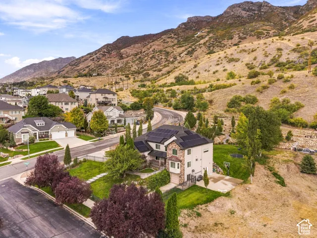 Modern residence featuring solar panels, stone and stucco exterior, multiple garages, and a sloped terrain backdrop