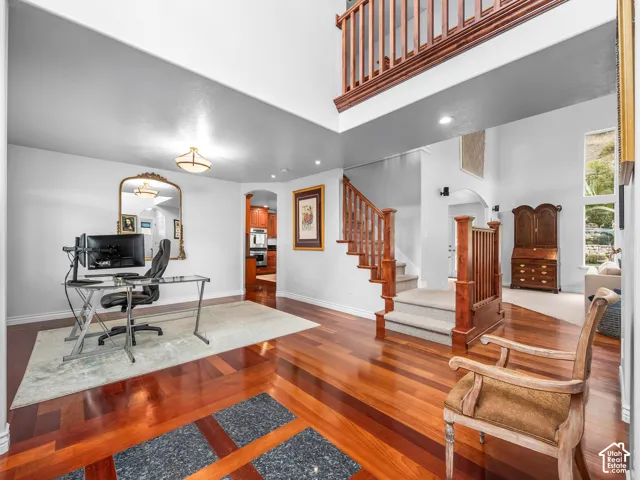 Hardwood flooring, recessed lighting, double-height ceiling, wood banister, and staircase with carpeted treads