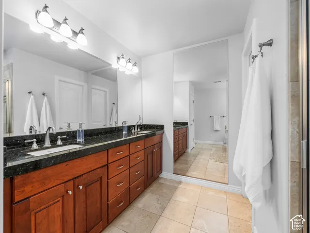 Dual vanity with wood-finish cabinetry, dark stone countertop, and undermount sinks