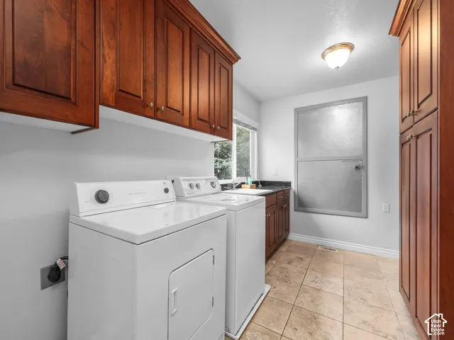 Extensive wood cabinetry, counter space with an integrated sink, tiled flooring, and a window