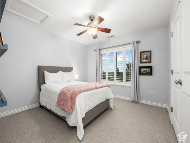 Carpeted flooring, window with plantation shutters, ceiling fan with integrated lighting, built-in shelving, and white door with brushed nickel hardware