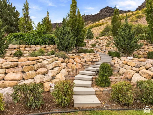 Tiered landscaping with natural stone retaining walls, integrated plantings, and a stepped pathway