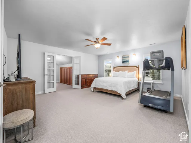 Spacious primary room featuring carpeting, a ceiling fan, and French doors