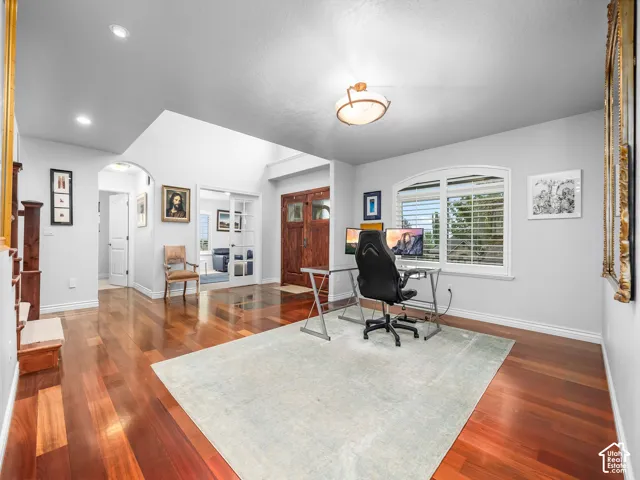 Hardwood flooring, arched entryway, window with plantation shutters, recessed lighting, and a vaulted ceiling