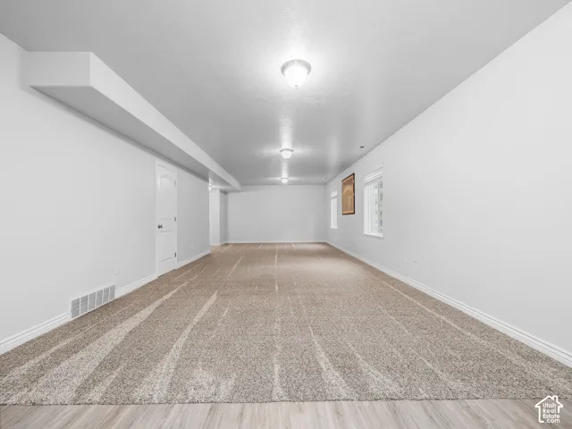 Expansive room featuring recessed lighting, light-toned carpeting, wood-finish flooring, and multiple windows