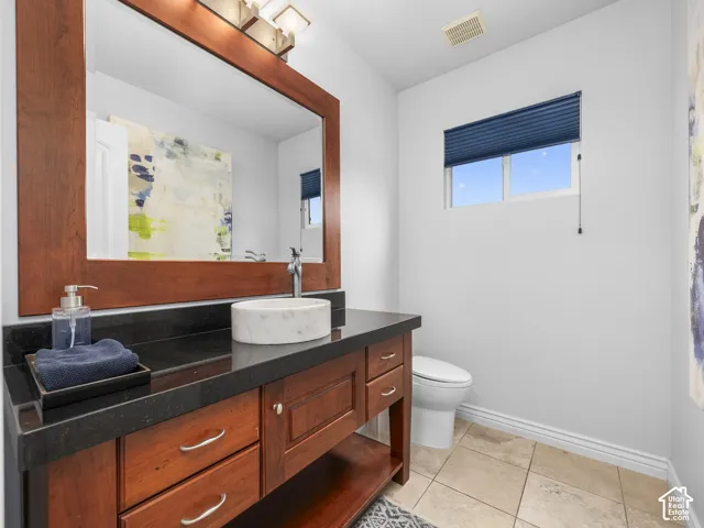 Wood-finish vanity with a vessel sink, dark countertop, and a large framed mirror