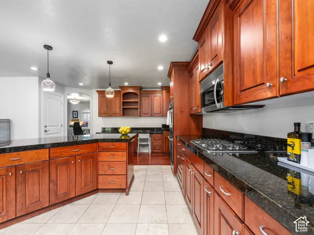 Kitchen featuring rich wood cabinetry, dark countertops, a built-in gas range, and recessed lighting