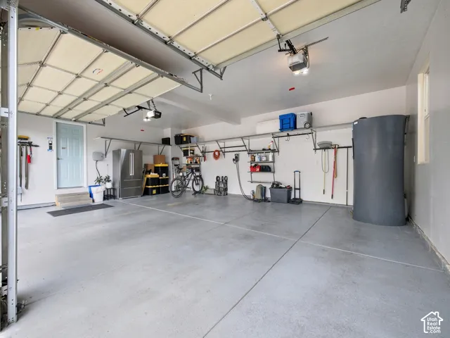 Two overhead garage doors, overhead lighting, finished concrete flooring, and wall-mounted shelving