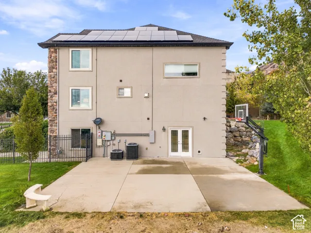 Stucco exterior with stone accent, solar panels, and a concrete patio