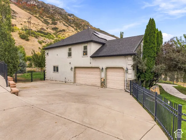 Stucco exterior with a multi-car garage, dark shingle roof, and a paved driveway