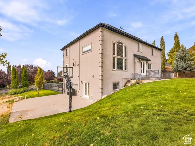 Stucco exterior with decorative corner quoining, a prominent multi-pane arched window, and multiple ground-level French doors