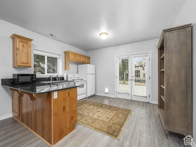 Kitchen area featuring wood-finish cabinetry, dark countertops, and wood-finish flooring
