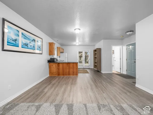 Wood-finish flooring, light grey walls, recessed and flush-mount lighting, wood cabinetry, and a glass-paneled exterior door