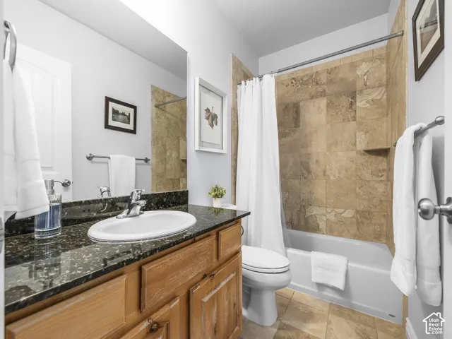 Bathroom featuring a single vanity with wood-finish cabinetry, black speckled countertop, and an undermount sink
