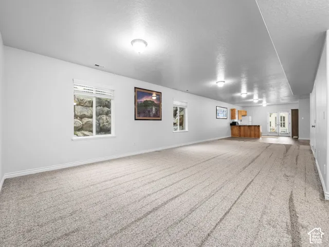 Spacious room featuring neutral carpet, recessed lighting, and a built-in wet bar with wood cabinetry