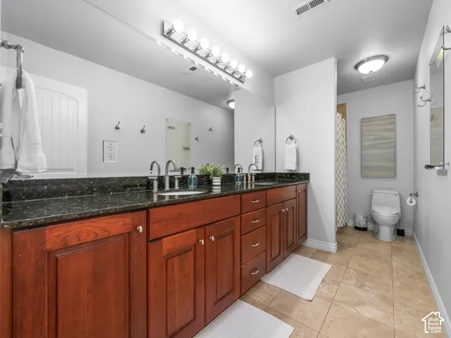 Double vanity with dark wood-finish cabinetry, dark countertop, and undermount sinks