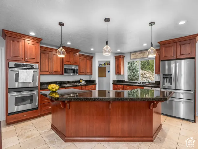 Rich wood cabinetry and a matching kitchen island featuring dark countertops