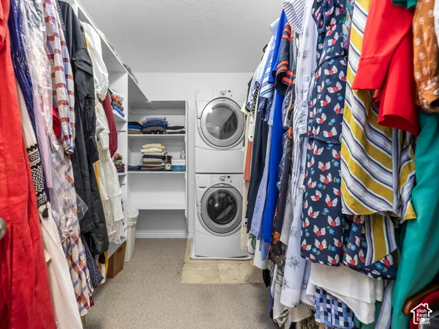 Built-in shelving, carpeted flooring, and a stacked washer and dryer
