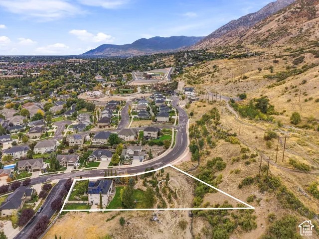 Expansive property featuring a mountain backdrop, a residential neighborhood, and a curved paved road