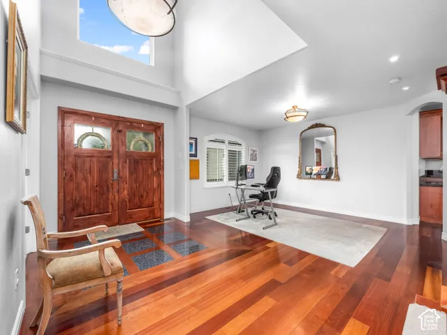 Double entry doors with glass accents, high ceilings, wood-finish flooring, formal dining with a large arched window.