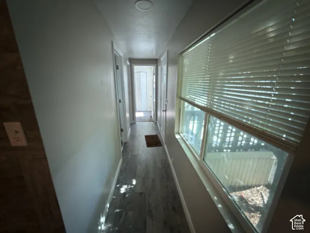 Hallway featuring wood-finish flooring, white walls, recessed lighting, and a large window with blinds