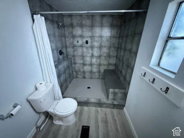Walk-in shower with tiled walls and a built-in bench, complemented by wood-finish flooring
