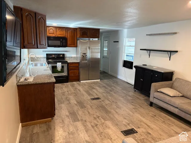 Wood-finish flooring throughout, complemented by a kitchen featuring granite-style countertops, wood cabinetry, and stainless steel appliances