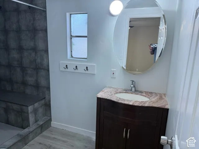 Vanity with a polished countertop, oval mirror, and a wall-mounted light fixture