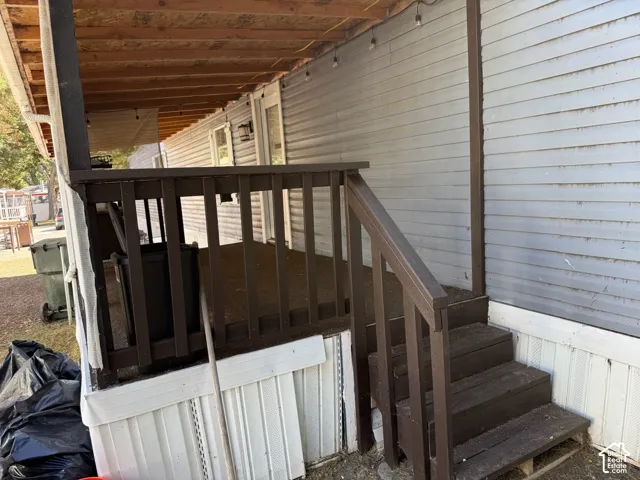 Exterior features a covered porch with wooden railings and steps, horizontal siding, and an exposed wood joist ceiling