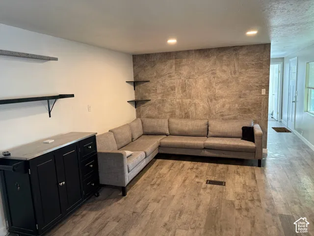 Recessed ceiling lighting, wood-finish flooring, and a textured accent wall