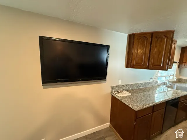 Wood-finish cabinetry, granite-style countertops, stainless steel sink, and a built-in dishwasher