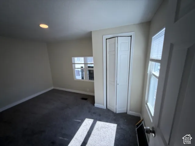 Recessed ceiling lighting, white bi-fold closet doors, white window blinds, and gray carpet flooring