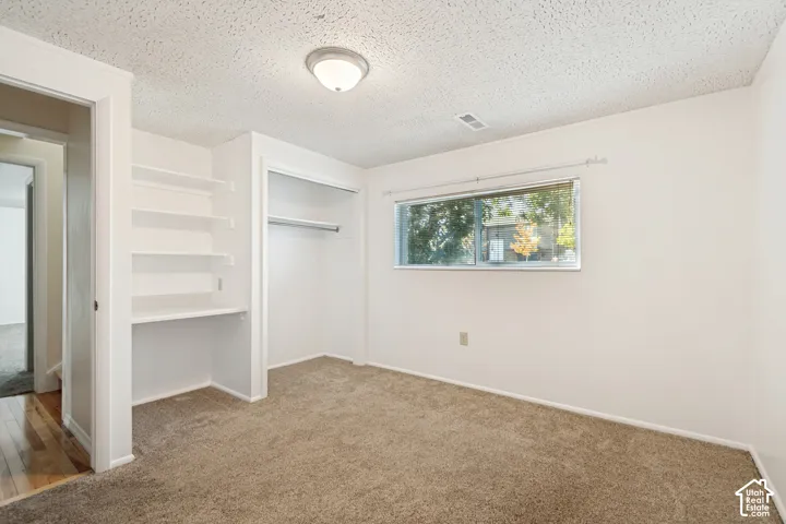 Basement bedroom featuring plush carpet flooring, recessed window, built-in shelving, integrated desk space, and a wardrobe closet.