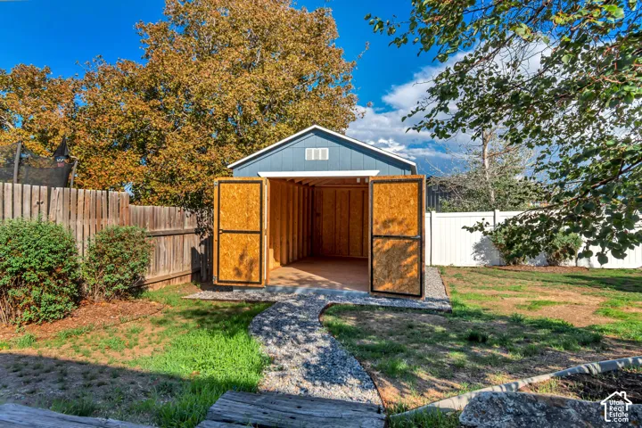 Detached storage shed with blue siding, a peaked roof, and double doors