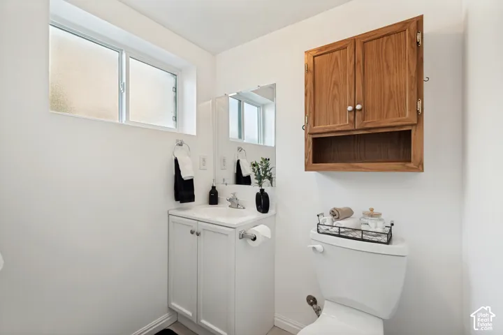 White vanity with a single basin sink, wall-mounted mirror, and wood-finish medicine cabinet