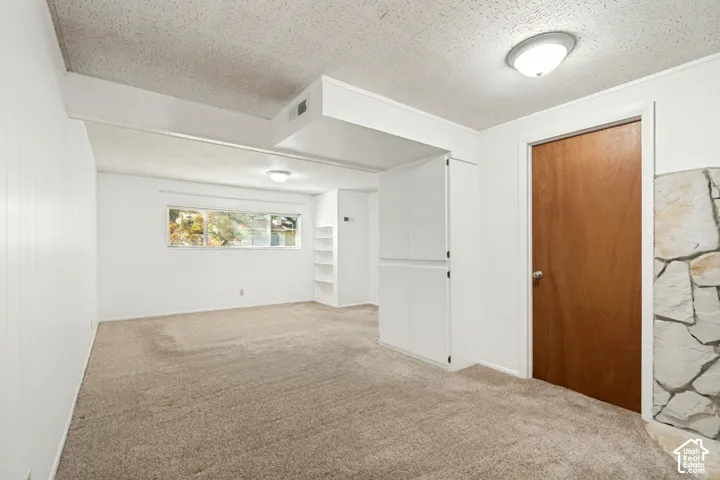 Neutral carpet flooring, white paneled walls, built-in shelving, two-panel windows, and flush-mount ceiling lights