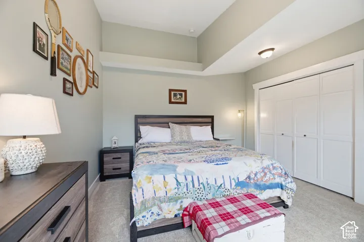 Vaulted ceiling with an upper accent shelf, neutral wall color, built-in closet with panel doors, and neutral carpet flooring