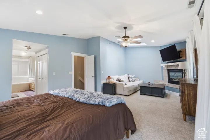 Spacious room with carpet flooring, a built-in fireplace with a stone surround, and an overhead ceiling fan