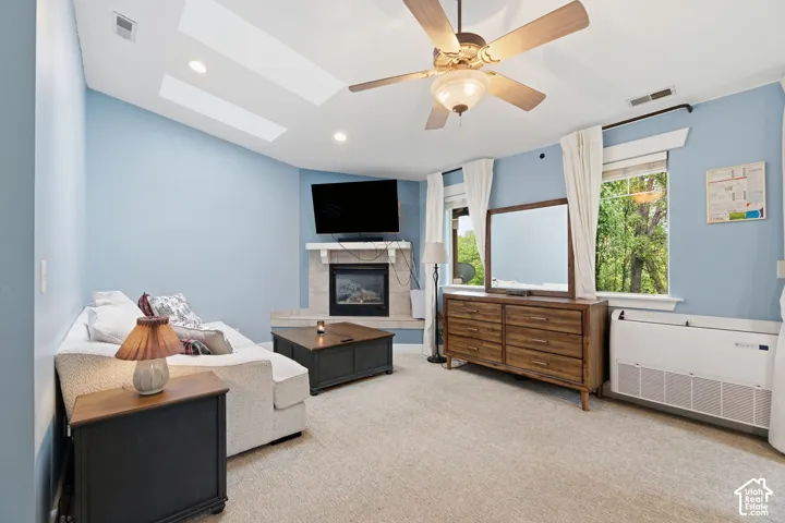 Built-in fireplace with stone surround, sloped ceiling, skylights, and ceiling fan
